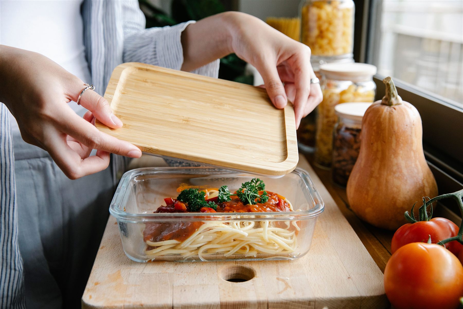 Preparando un menú casero en tápers de cristal, con verduras frescas alrededor