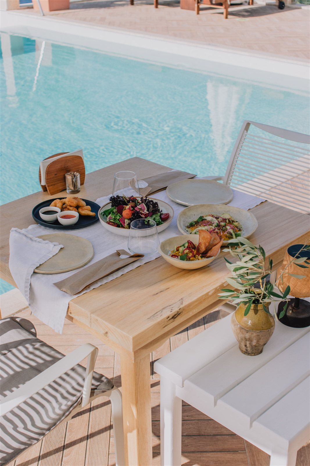 Mesa junto a la piscina de un hotel con platos vegetales servidos